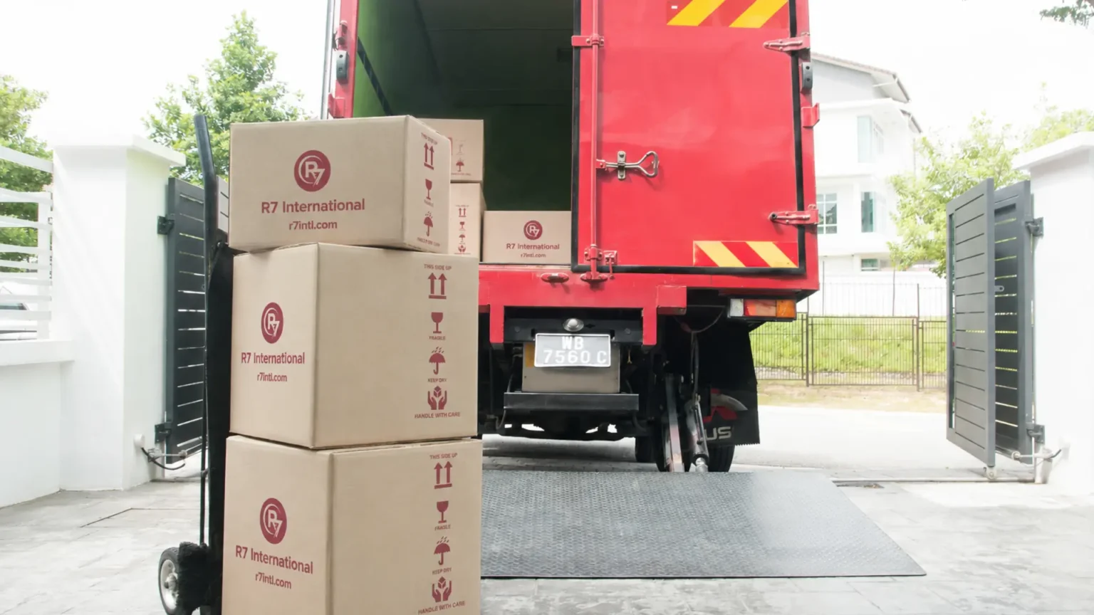 R7 International branded cartons stacked on a trolley beside an open red moving truck